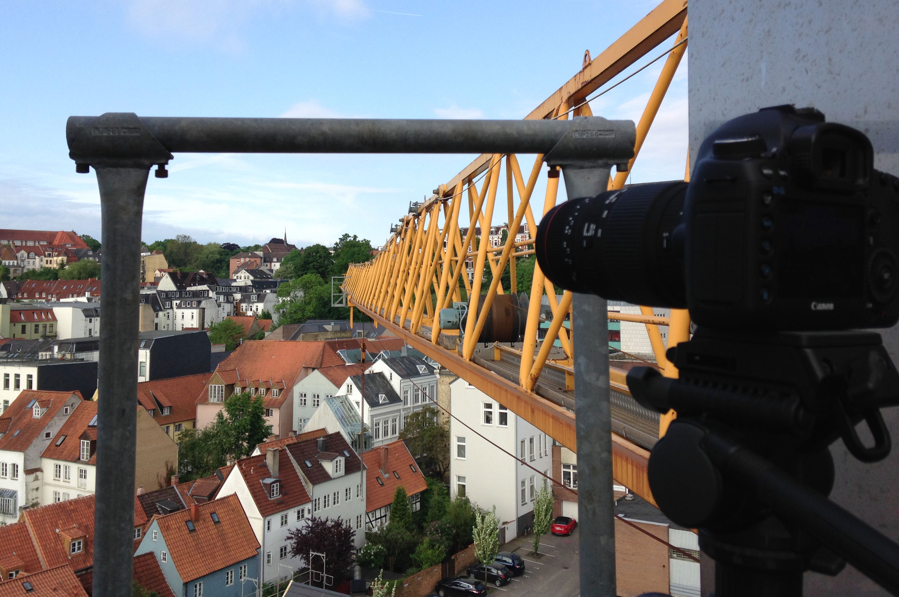 Kamera auf Stativ fotografiert von einem Kran aus Häuserdächer.