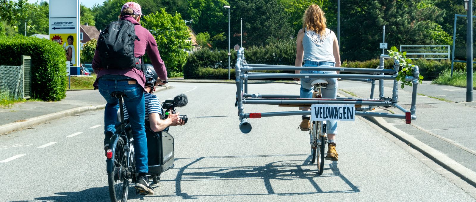 A bike with dimensions of a car is beeing filmed on the road.