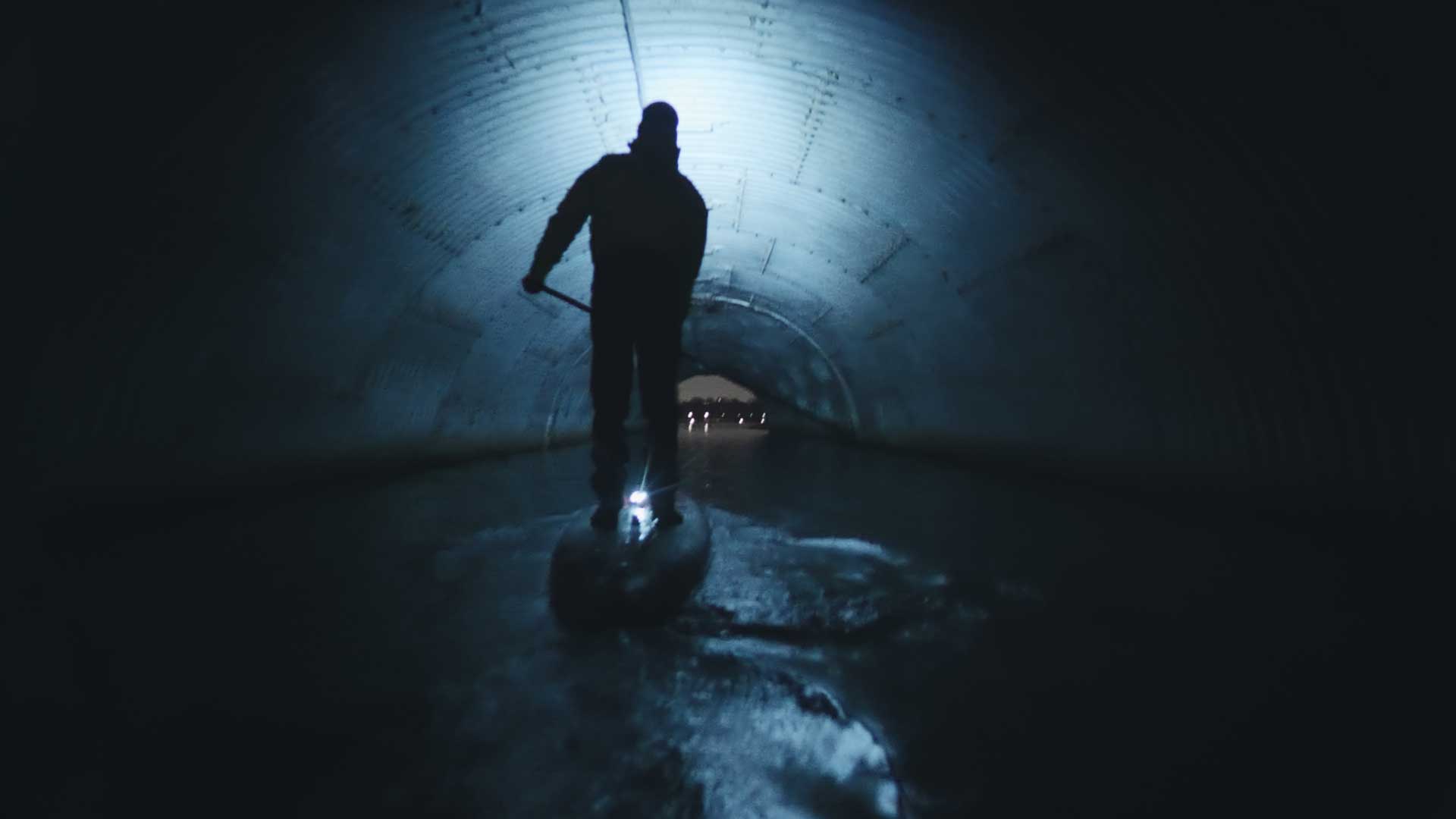 SUP Paddler gliding through a dark tunnel at night.